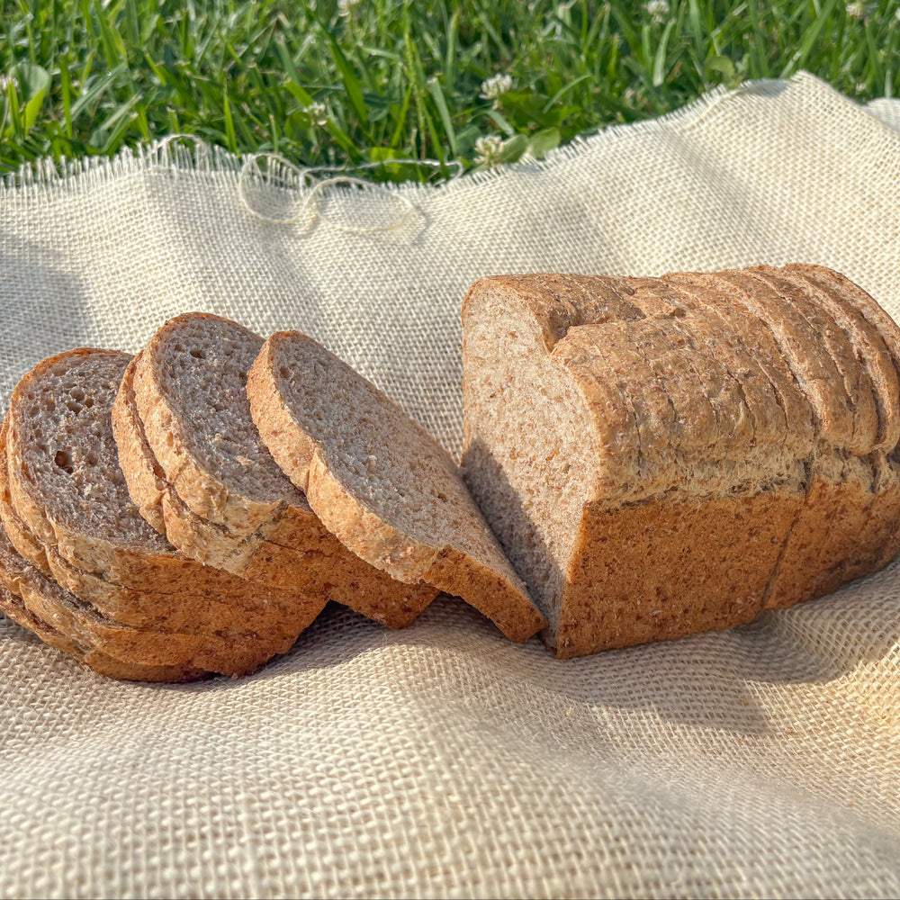 Sliced whole grain bread on a white cloth with grass in the background