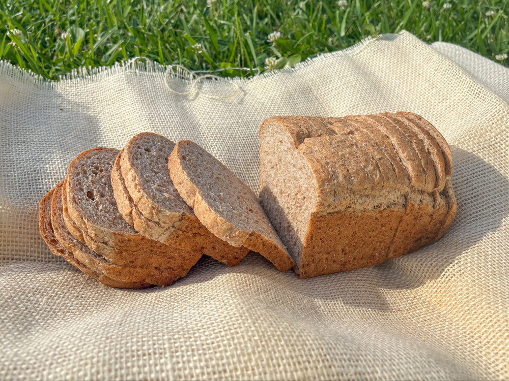 Sliced whole grain bread on a white cloth with grass in the background